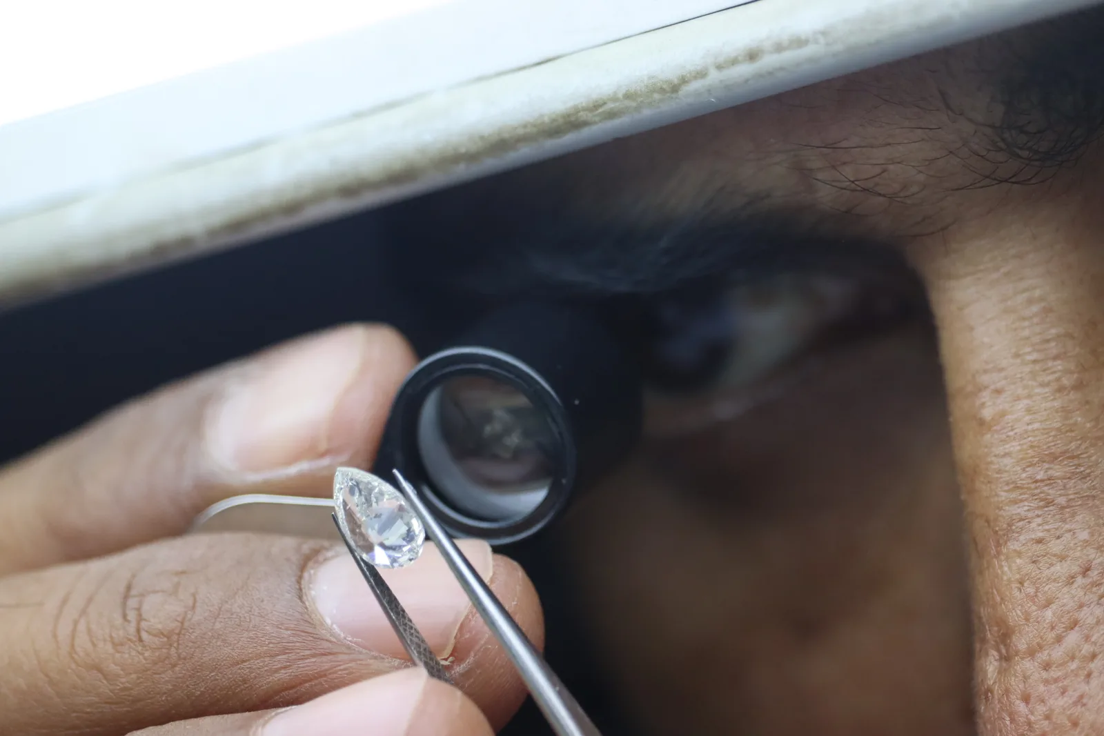 Gemologist inspecting a diamond by hand with a loupe